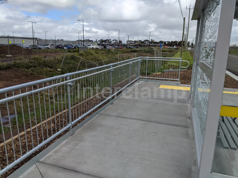 Safety barriers at a bus stop constructed using Interclamp pedestrian barriers and key clamp DDA assist rail, ensuring a safe environment for passengers.